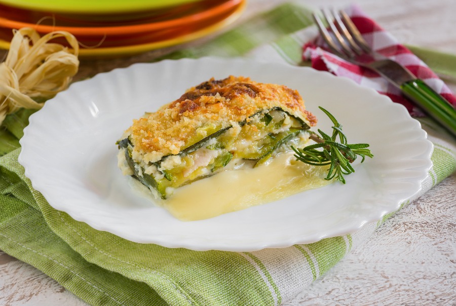 Pastel de pescado gratinado con una capa de queso derretido y acompañado de romero fresco en un plato